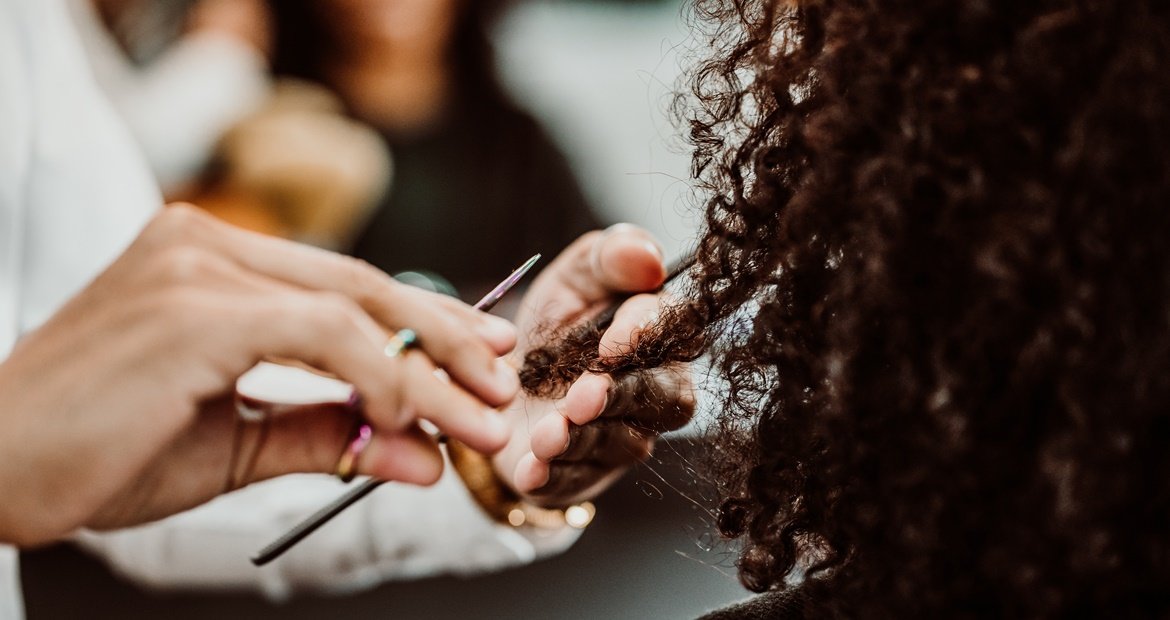 Cabeleireiro fazendo o corte wolf cut cacheado no cabelo cacheado da cliente.